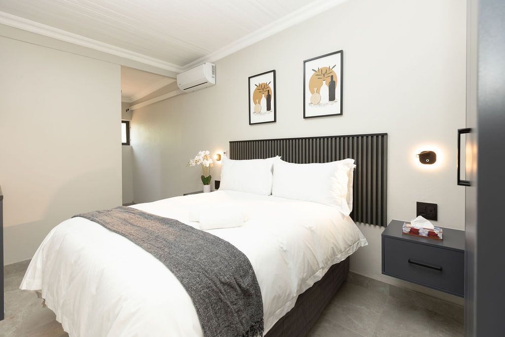 En-suite double bedroom with a slatted headboard and crisp white linen